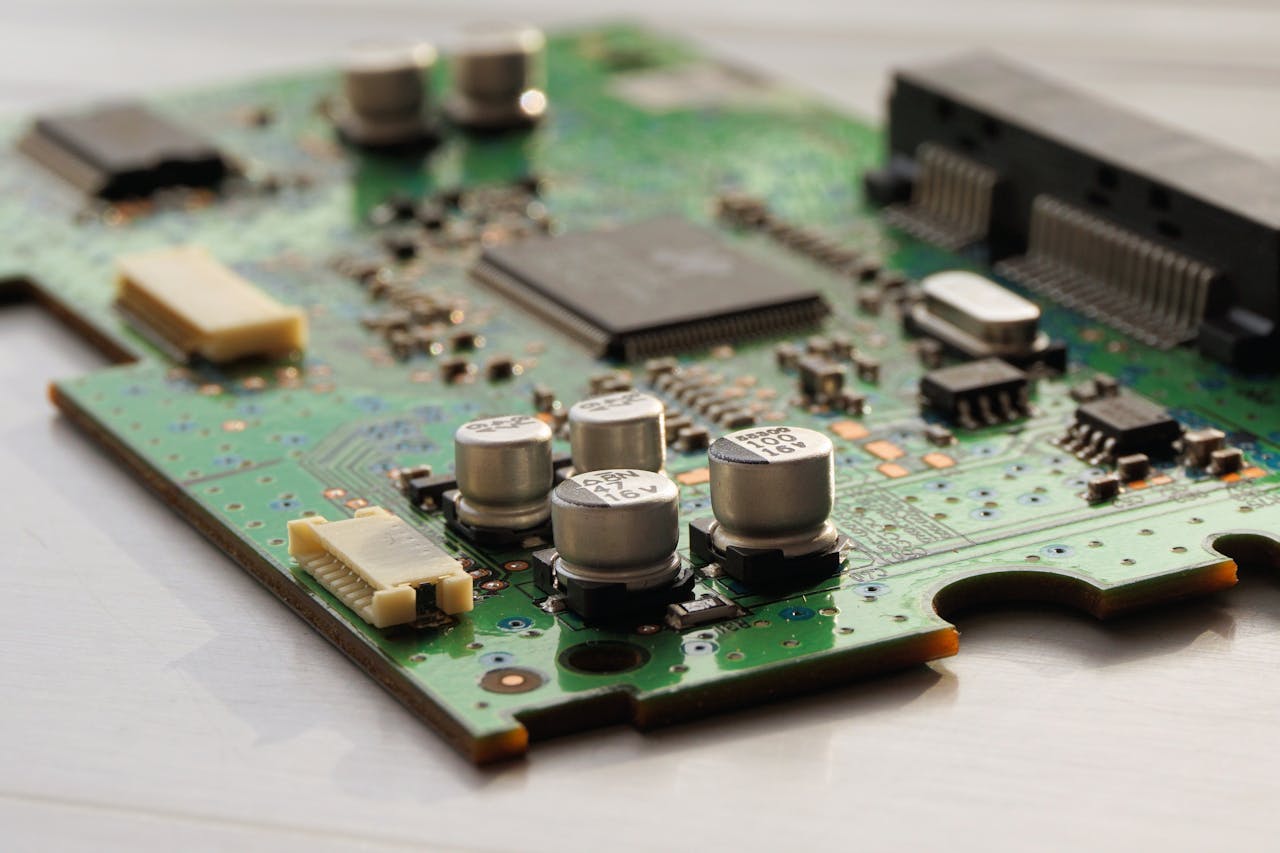 services-02 Detailed view of a green circuit board featuring capacitors and microchips.
